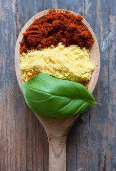 Assorted spices with basil in a wooden spoon