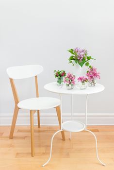 Elegant interior with white table and chair, decorated with bouquets of spring flowers.