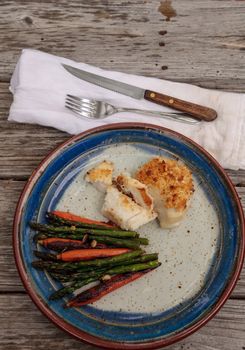 White flakey sea bass with breadcrumbs and roasted asparagus and carrots in summer