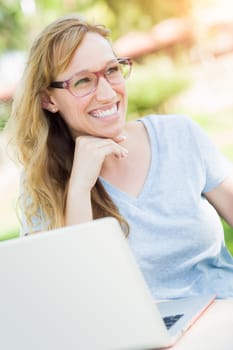 Young Adult Woman Wearing Glasses Outdoors Using Her Laptop.