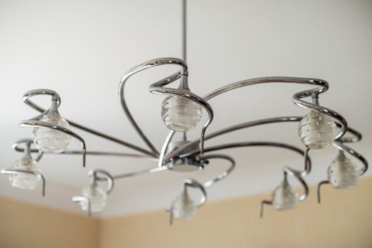 metal chandelier with glass shades hanging on the white ceiling