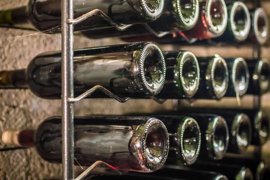 bottles of red wine lying on an iron shelf