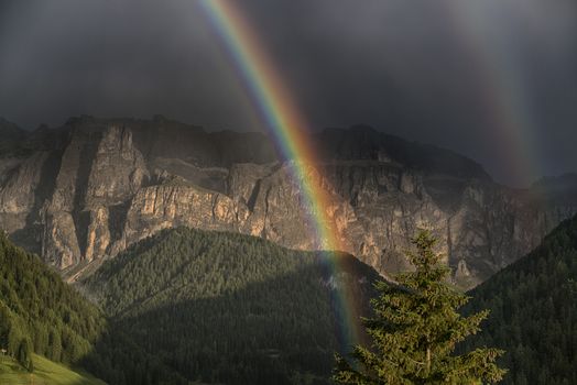 Rainbow after the thunderstorm over the hills and mountains of Selva di Val Gardena in a summer end of the day, Trentino-Alto Adige - Italy
