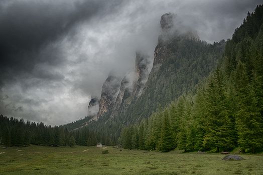 Green valley and clouds over the top of the mountains of Vallunga in a rainy summer day, italian alps