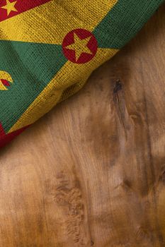 Flag of Grenada from rough burlap on a wooden background