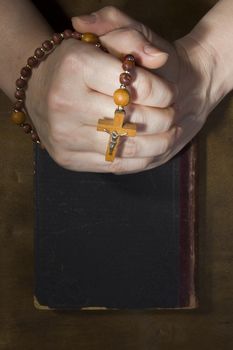 Female hands with rosary and an old book