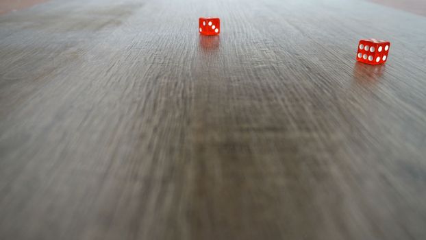 Throwing red dice on a grey background in the casino. Slow motion.