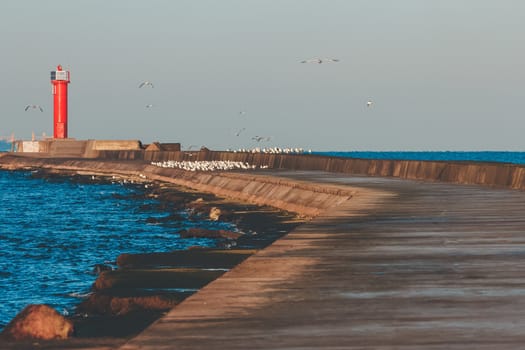 Red lighthouse on breakwater jetty at Baltic sea