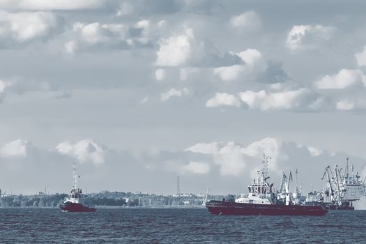 Two tug ships are accepting cargo vessel at Daugava river