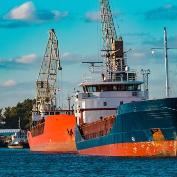 Blue cargo ship moored and loading at the port