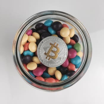 Cryptocurrency physical silver bitcoin coin with yellow sign in colorful composition.