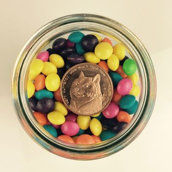Digital currency physical brass dogecoin coin in glass jar.