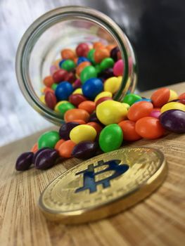 Digital currency physical gold bitcoin coin on the wooden board near colorful sweets