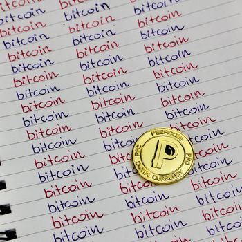 Digital currency physical small gold peercoin coin in bitcoin notebook.