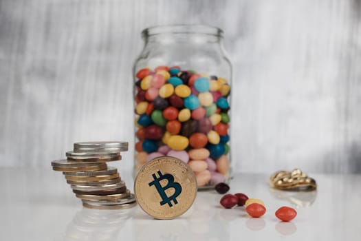 Digital currency physical gold bitcoin coin on the table near jelly sweets.
