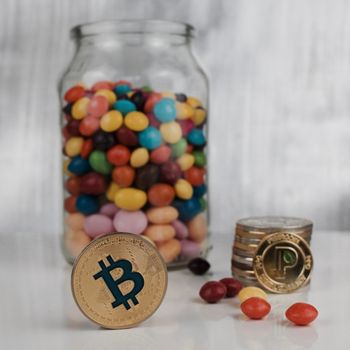 Digital currency physical gold bitcoin coin and gold peercoin coin near sweets.