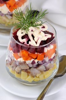 Salad of chopped herring with onions, potatoes, beets, carrots, seasoned with yogurt sauce in a glass