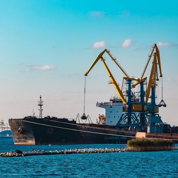 Black cargo ship loading with a coal at the port