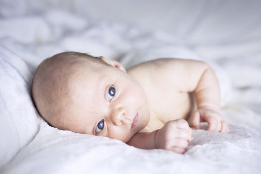 Beautiful baby girl on white blanket. Studio shot