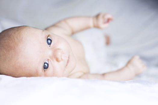 Beautiful baby girl on white blanket. Studio shot