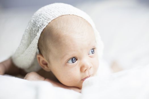 Beautiful baby girl on white blanket. Studio shot