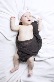 Beautiful baby girl on white blanket. Studio shot