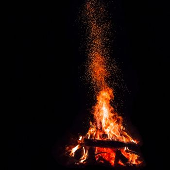 Campfire with flying sparks isolated on black background