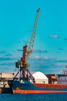 Blue cargo ship moored and loading at the port