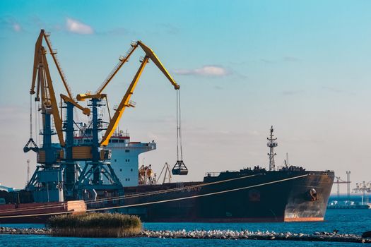 Black cargo ship loading with a coal at the port