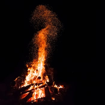 Campfire with flying sparks isolated on black background