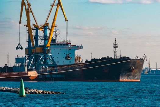 Black cargo ship loading with a coal at the port