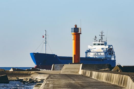 Blue cargo ship sailing against the breakwater dam