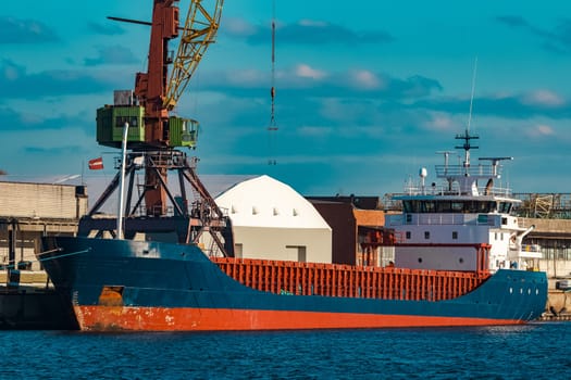 Blue cargo ship moored and loading at the port