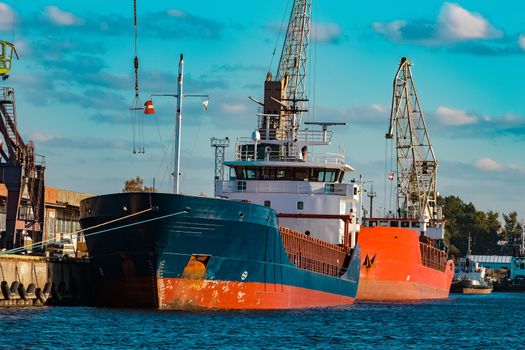 Blue cargo ship moored and loading at the port