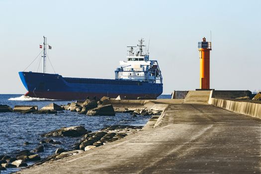 Blue cargo ship sailing against the breakwater dam