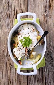 Potatoes and mushrooms topped with sour cream in a casserole dish