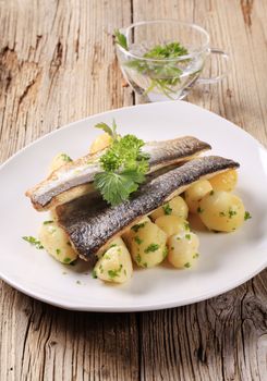 Pan fried trout with potatoes on wooden background