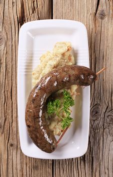 White pudding and mashed potato with peeled barley on wooden background