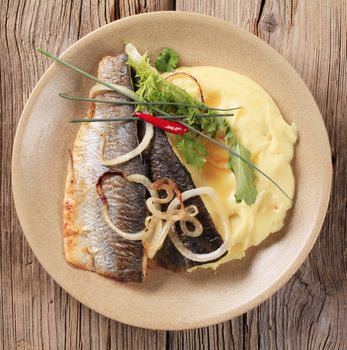 Pan fried trout with mashed potatoes on wooden background