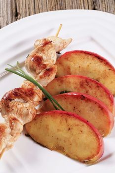 Chicken skewer and slices of baked apple