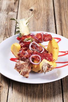 Meat skewers and crispy bacon strips served on pineapple peel