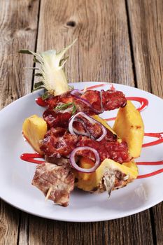 Meat skewers and crispy bacon strips served on pineapple peel