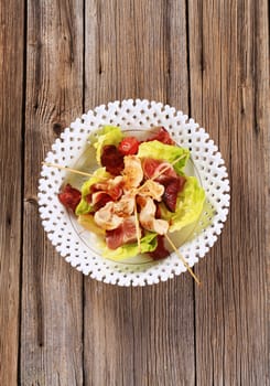 Chicken skewers and bacon served on lettuce leaves