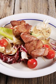 Pork kebab on a wooden skewer with vegetables