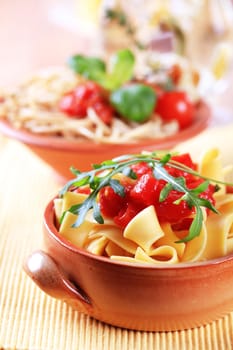 Ribbon pasta and diced tomato topped with arugula