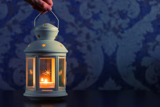 beautiful white lantern in hand. blue background