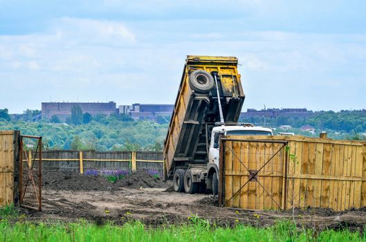The dumper brought and dumps earth in the open warehouse.