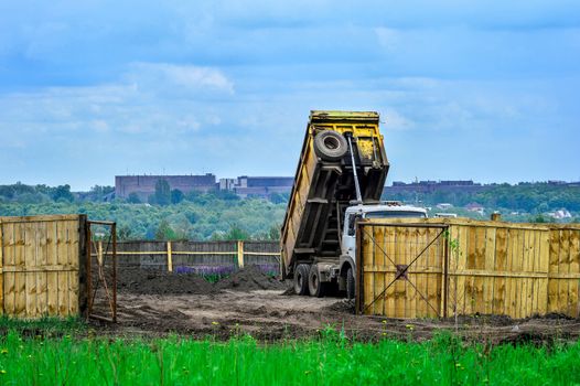 The dumper brought and dumps earth in the open warehouse.
