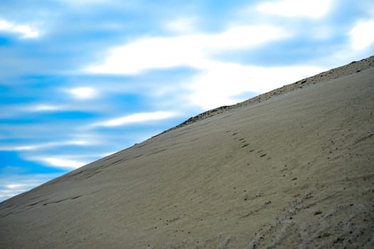 Sandy hill in a quarry against the sky.