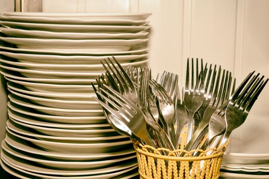 A stack of washed dishes and forks in the kitchen.